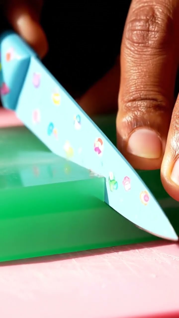 AI-generated ASMR video frame: Emerald glass with a candy-themed knife